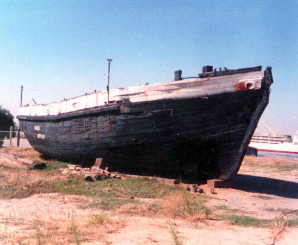 This image shows hulk of ship without masts on land.