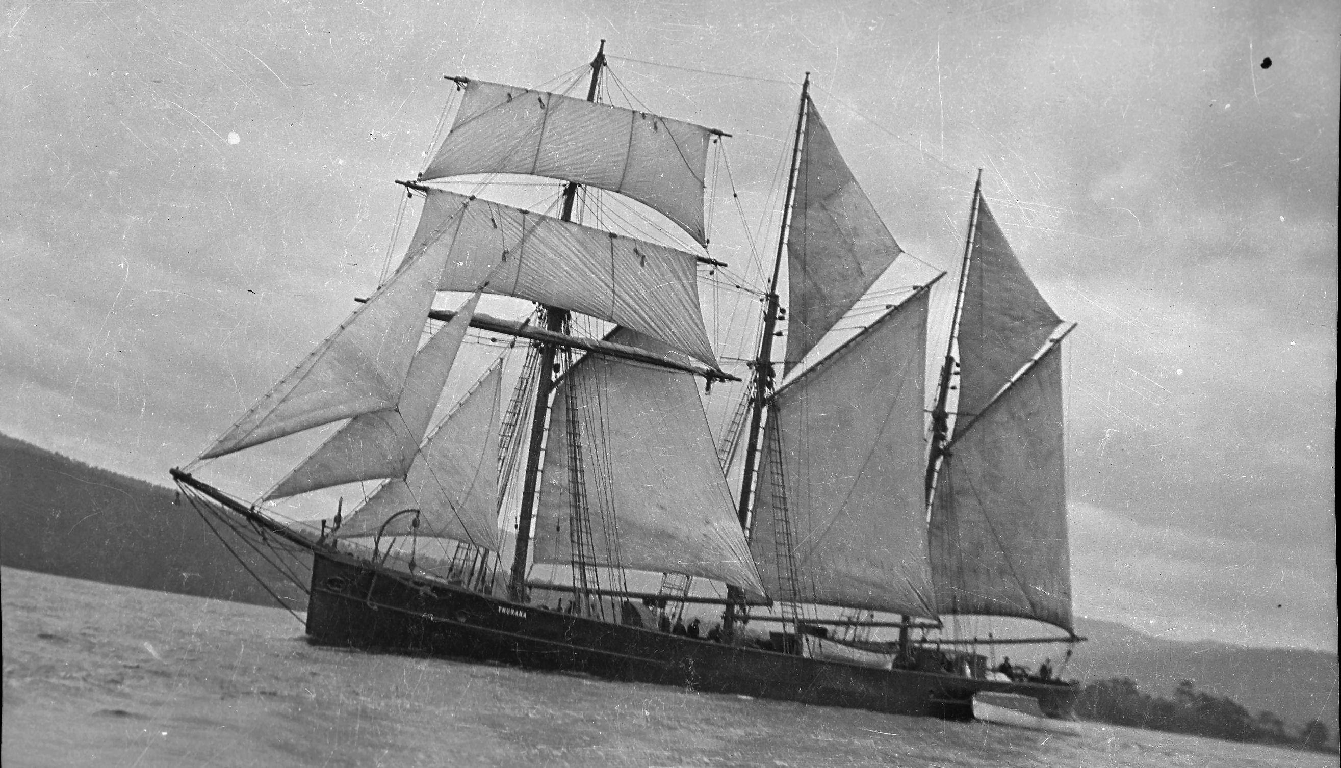 Image: three masted topsail schooner on water, sails fully unfurled