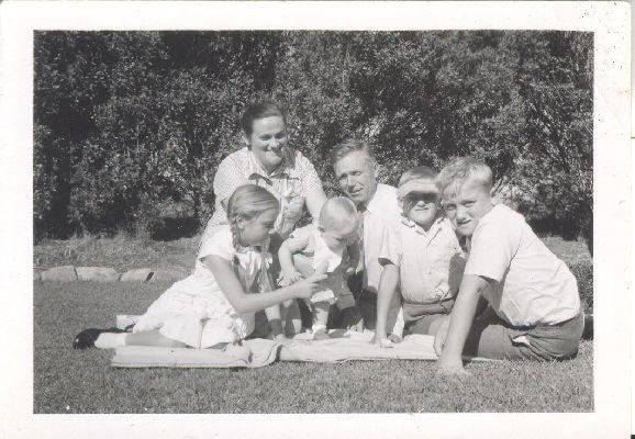 Image: family sitting together on grass, man and woman behind children