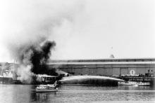 1942 Police Launch at Port Adelaide with fire on vessel in the background being extinguished by fireboat