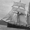 Image: three masted topsail schooner on water, sails fully unfurled